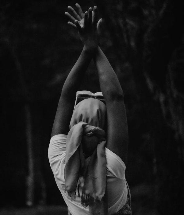 A woman in a peaceful yoga pose against a dark background.